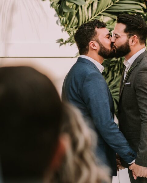 men wearing suit kissing in front of people