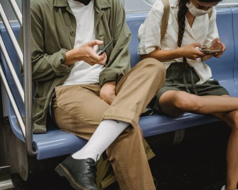 crop couple browsing smartphones in subway carriage